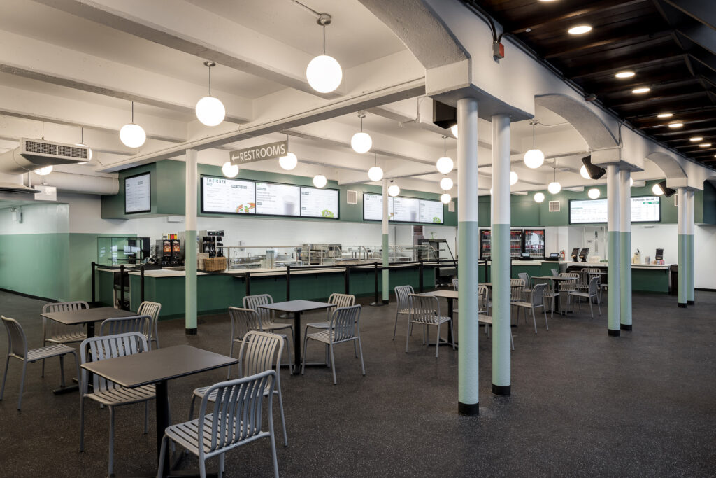 The Wollman Café dining room, with café tables under globe pendant lights and the service counter behind